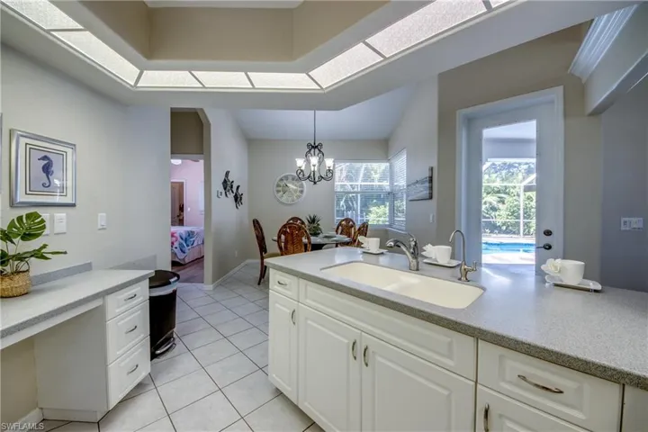 Kitchen featuring decorative light fixtures, an inviting chandelier, light tile floors, sink, and white cabinets