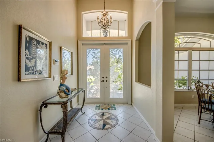 Foyer with a chandelier, french doors, a high ceiling, and light tile floors