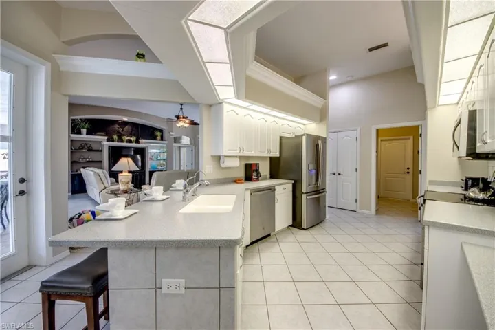 Kitchen featuring white cabinets, ceiling fan, a breakfast bar area, appliances with stainless steel finishes, and sink