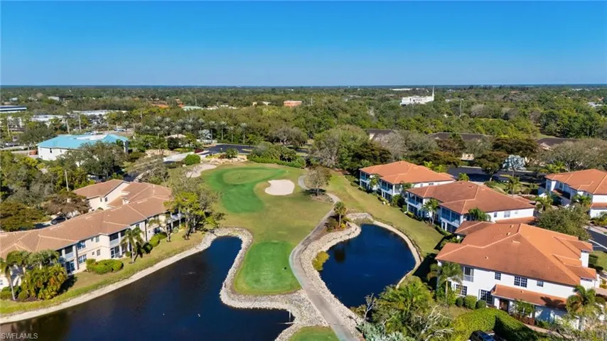 Aerial view of property and surrounding area featuring a large body of water, nearby suburban area, and a golf course