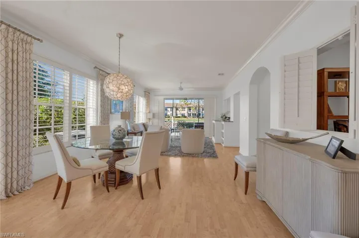 Dining room featuring ornamental molding, laminate flooring, ceiling fan, and arched walkways