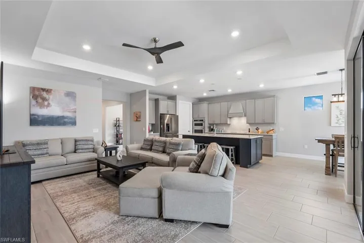 Living area with a tray ceiling, ceiling fan, recessed lighting, and wood tiled floors