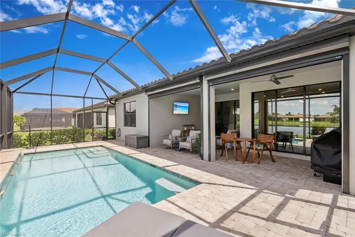 Outdoor pool with a patio area, a grill, and a lanai