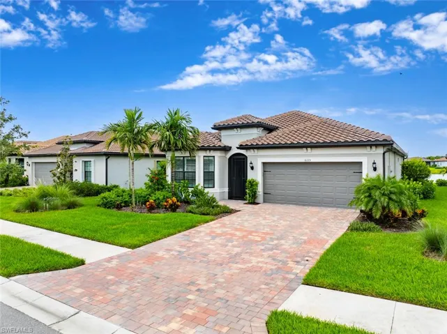 Mediterranean / spanish home with an attached garage, a front lawn, stucco siding, decorative driveway, and a tiled roof