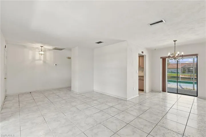 White tile flooring throughout, sliding glass doors, and a chandelier lighting fixture