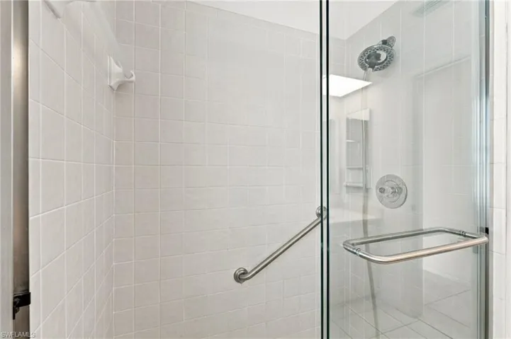 Glass-enclosed shower featuring subway tile, chrome fixtures, and a grab bar