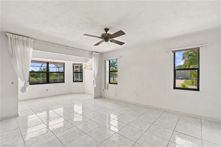 White ceramic tile flooring, multiple windows, ceiling fan, and wall-mounted light fixture