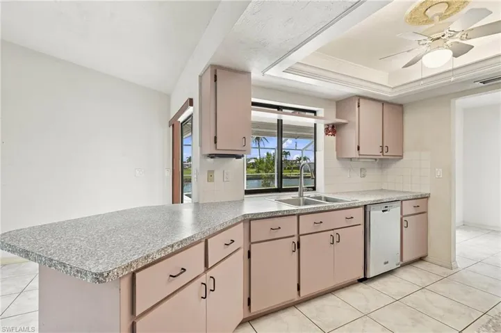 Kitchen featuring ample cabinetry, a double basin sink, dishwasher, and tile flooring