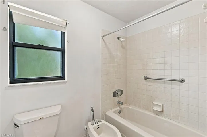 White tiled shower/tub combination with chrome fixtures
