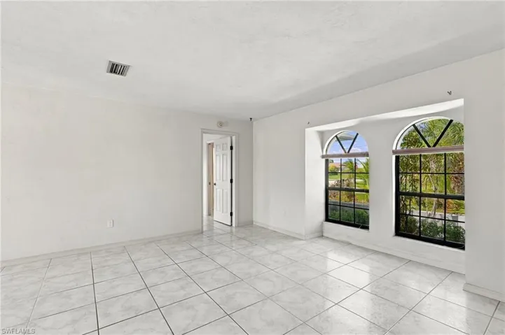 Tile flooring, arched windows, and white walls