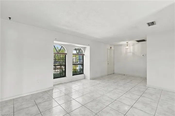 White tile flooring, arched windows, built-in recessed lighting, and a pendant light fixture