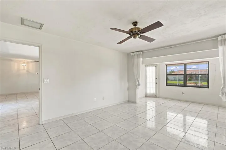 White tile flooring throughout, ceiling fan with light fixture, and a large window providing ambient light