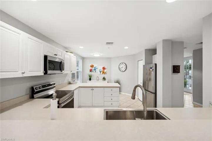 Kitchen featuring appliances with stainless steel finishes, white cabinetry, sink, and light tile patterned flooring
