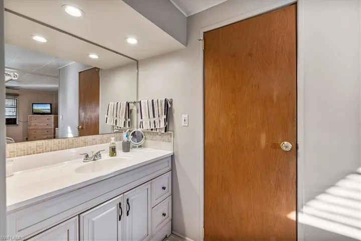 Bathroom featuring vanity, recessed lighting, and tasteful backsplash