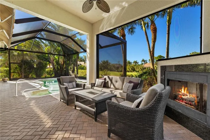 View of patio / terrace featuring a lanai, an outdoor living space with a fireplace, and an outdoor pool