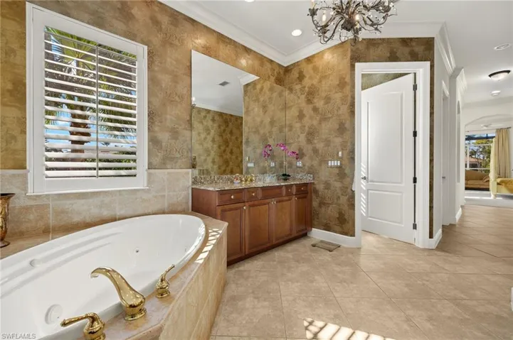 Full bath featuring ornamental molding, tile patterned flooring, and a jetted tub