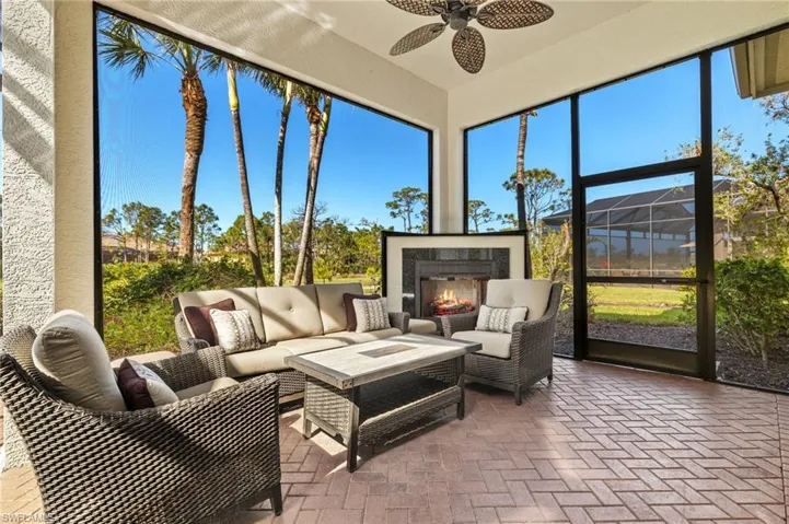 Sunroom / solarium featuring a healthy amount of sunlight, a warm lit fireplace, and ceiling fan