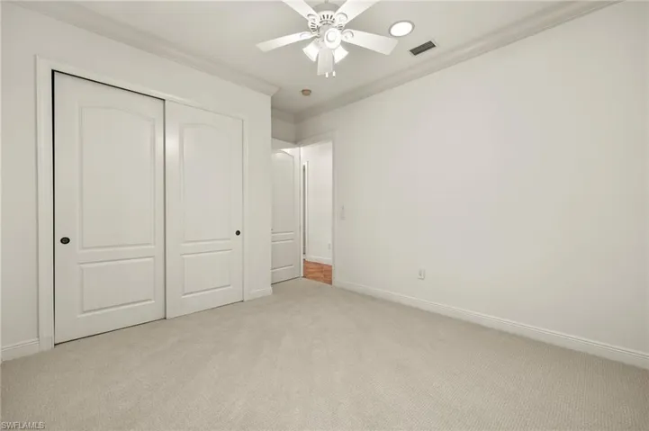 Unfurnished bedroom with visible vents, baseboards, a closet, carpet, and crown molding