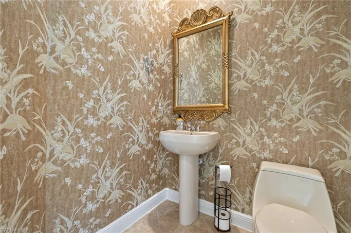 Half bathroom with toilet, baseboards, and tile patterned floors