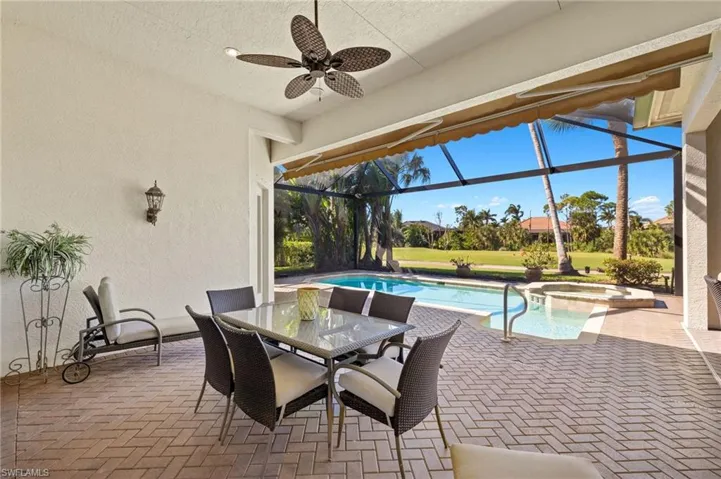 View of patio / terrace with a lanai, a pool with connected hot tub, outdoor dining area, and a ceiling fan