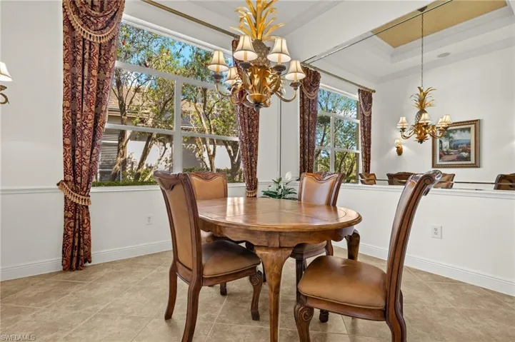 Dining space featuring baseboards, ornamental molding, a raised ceiling, and an inviting chandelier