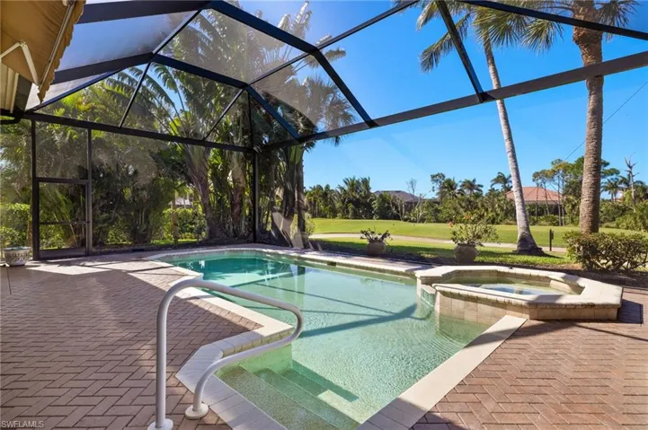 View of swimming pool with a pool with connected hot tub, glass enclosure, a yard, and a patio