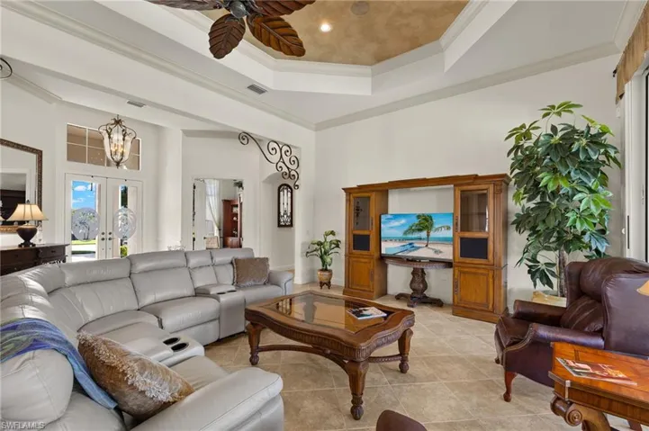 Living area with a tray ceiling, french doors, crown molding, light tile patterned floors, and visible vents