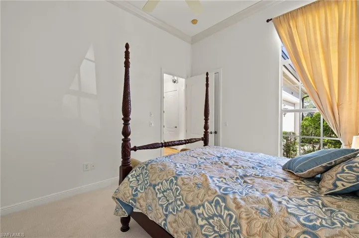 Carpeted bedroom featuring ceiling fan, baseboards, and crown molding