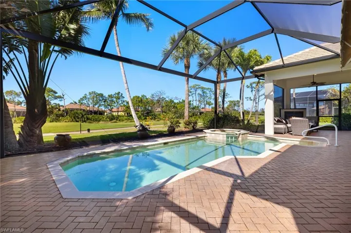 View of pool featuring ceiling fan, a lanai, a pool with connected hot tub, a yard, and a patio area