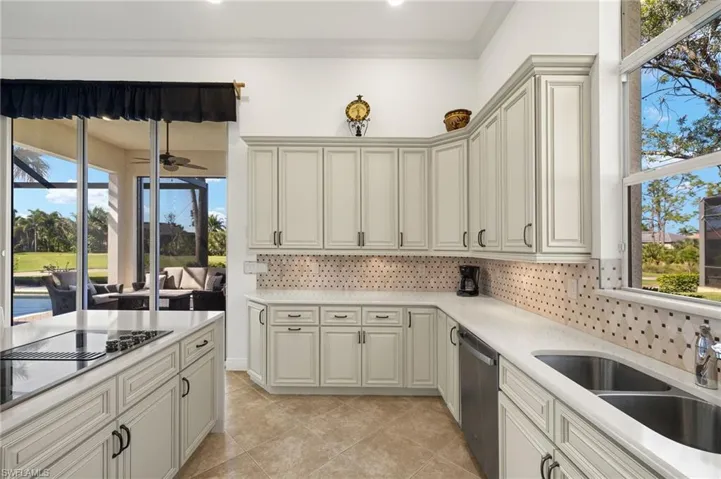 Kitchen with tasteful backsplash, light countertops, crown molding, stainless steel dishwasher, and a sink