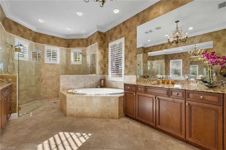 Full bathroom featuring an inviting chandelier, plenty of natural light, a tile shower, and vanity