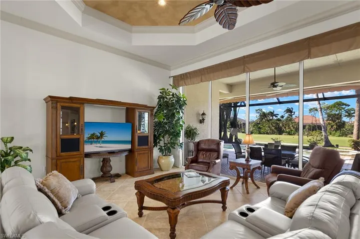 Living area featuring ornamental molding, a tray ceiling, ceiling fan, and light tile patterned floors