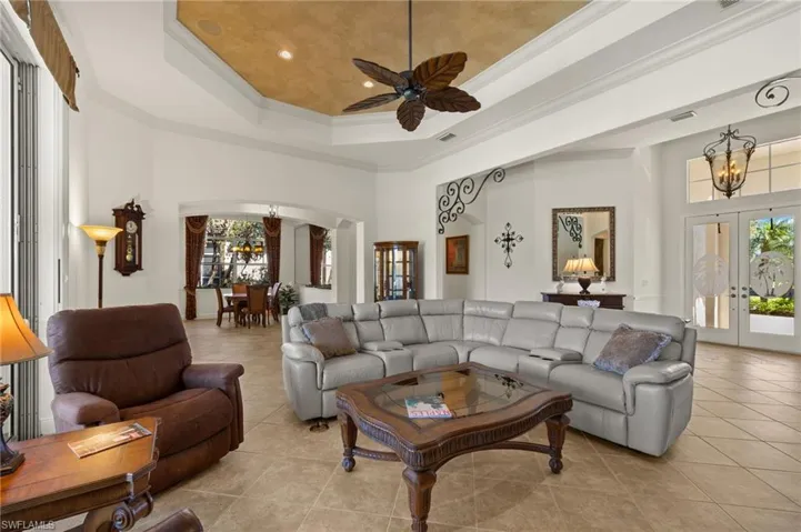 Living area with a healthy amount of sunlight, arched walkways, a tray ceiling, and french doors