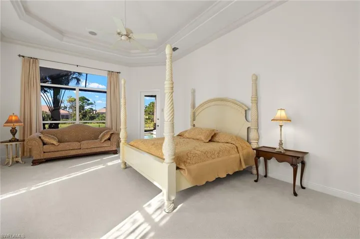 Carpeted bedroom featuring ceiling fan, baseboards, access to outside, a raised ceiling, and crown molding