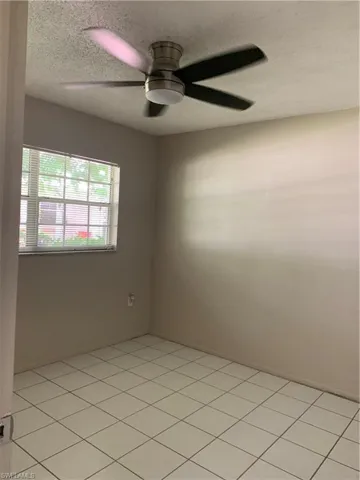 Spare room featuring light tile patterned flooring, a textured ceiling, and ceiling fan