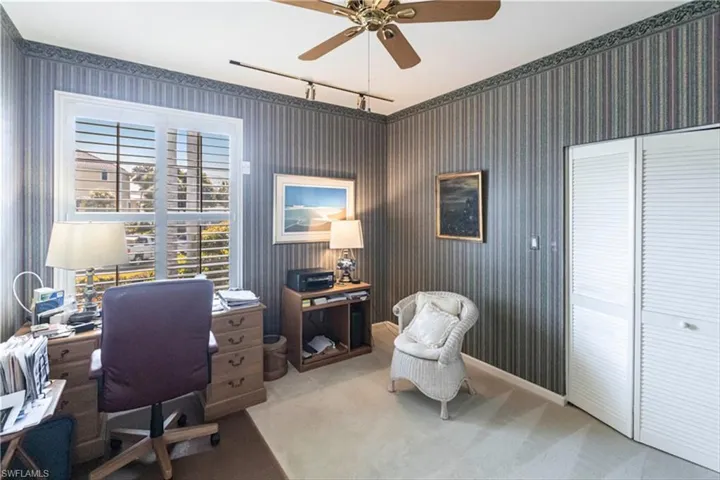 Carpeted office with track lighting and ceiling fan