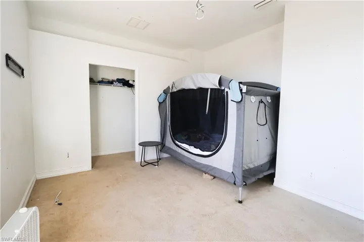 Bedroom featuring light carpet and baseboards