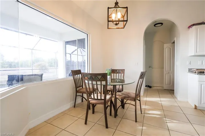 Dining room with arched walkways, light tile patterned flooring, and suspended lighting