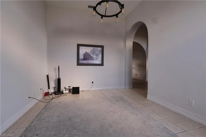 Unfurnished room with light tile patterned flooring and arched walkways