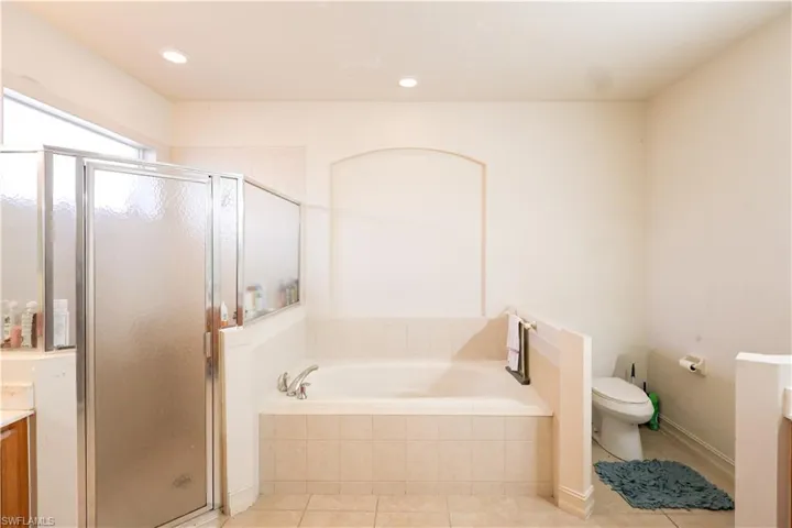Bathroom with vanity, a shower stall, light tile patterned floors, a bath, and recessed lighting