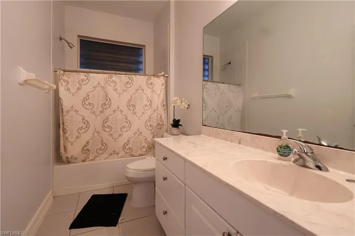 Bathroom with vanity, shower / tub combo with curtain, and light tile patterned floors