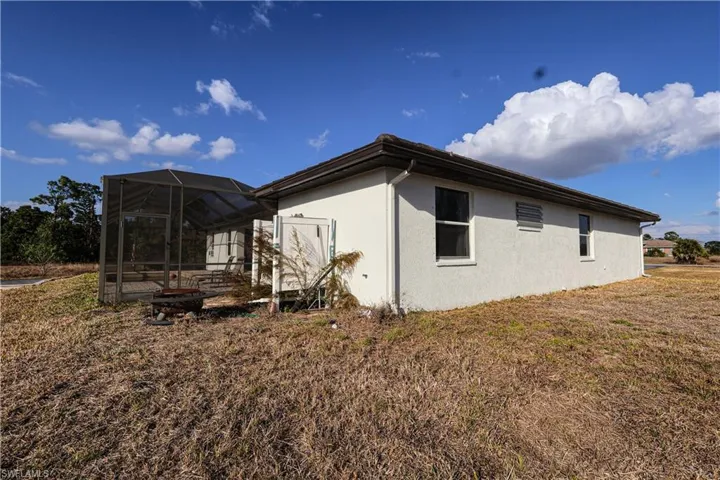 View of side of home featuring glass enclosure, a sunroom, stucco siding, and a yard