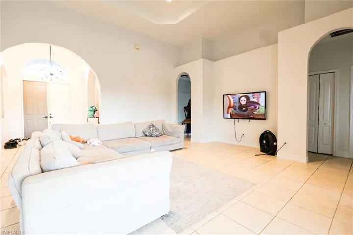 Living room with arched walkways, a high ceiling, light tile patterned floors, and hanging lights