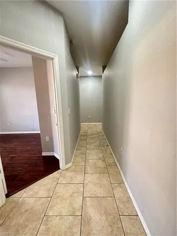 Corridor with light tile patterned floors and a textured wall