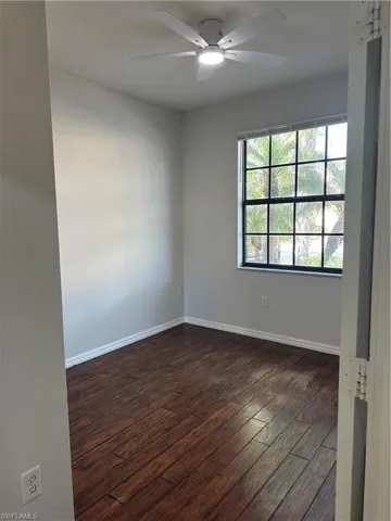 Spare room featuring dark wood-style flooring and a ceiling fan
