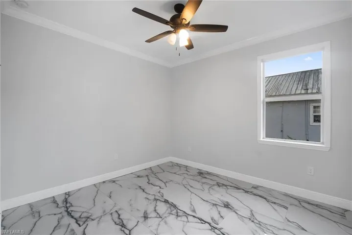 Spare room with ceiling fan and ornamental molding