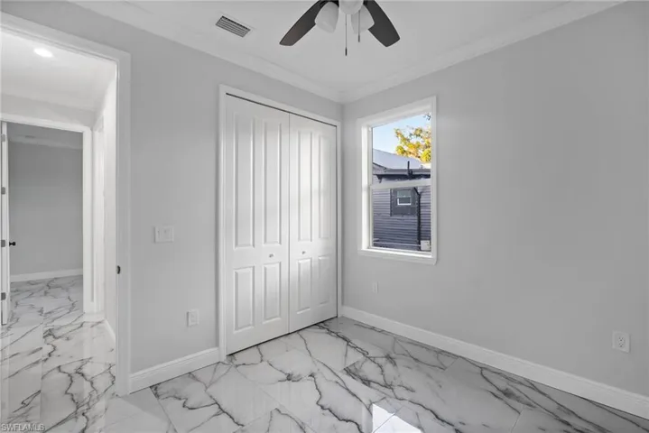 Unfurnished bedroom with ceiling fan, ornamental molding, and a closet