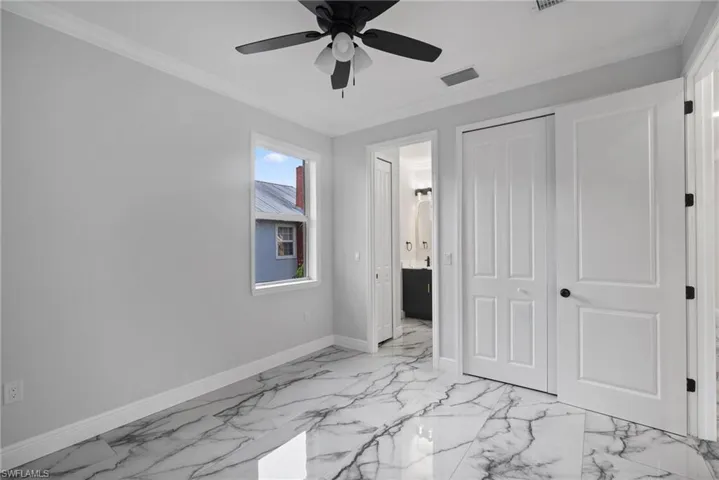 Unfurnished bedroom featuring ceiling fan, ornamental molding, and a closet