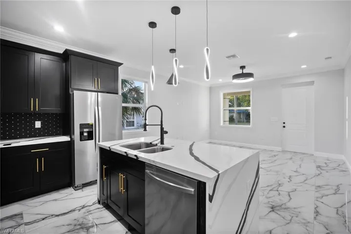 Kitchen featuring appliances with stainless steel finishes, a center island with sink, a healthy amount of sunlight, and sink