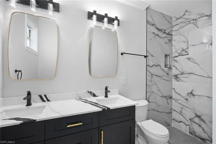 Bathroom featuring toilet, vanity, and tiled shower